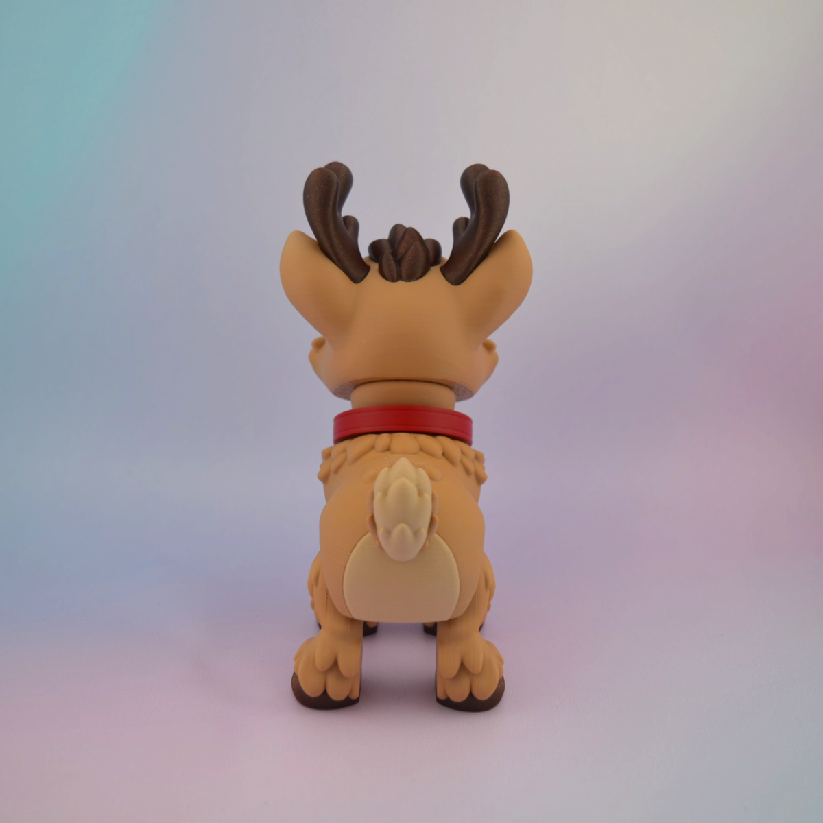 3D printed Christmas reindeer with big brown eyes, a bright red nose, brown antlers and a red collar with a golden bell.
