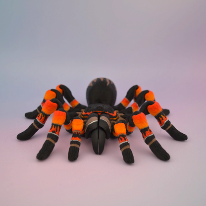 3D printed black tarantula with vibrant orange markings on its legs, displayed against a plain background.