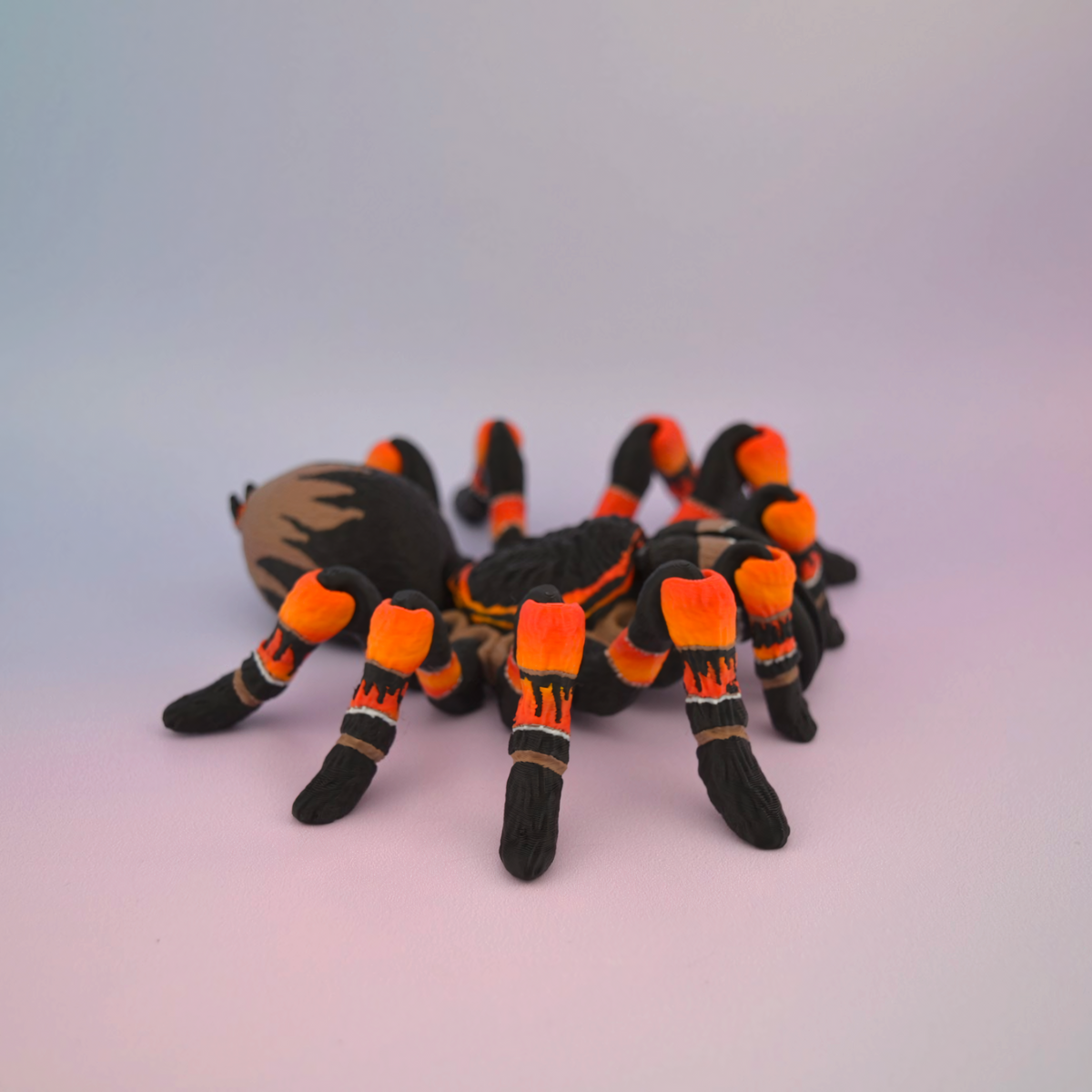 3D printed black tarantula with vibrant orange markings on its legs, displayed against a plain background.