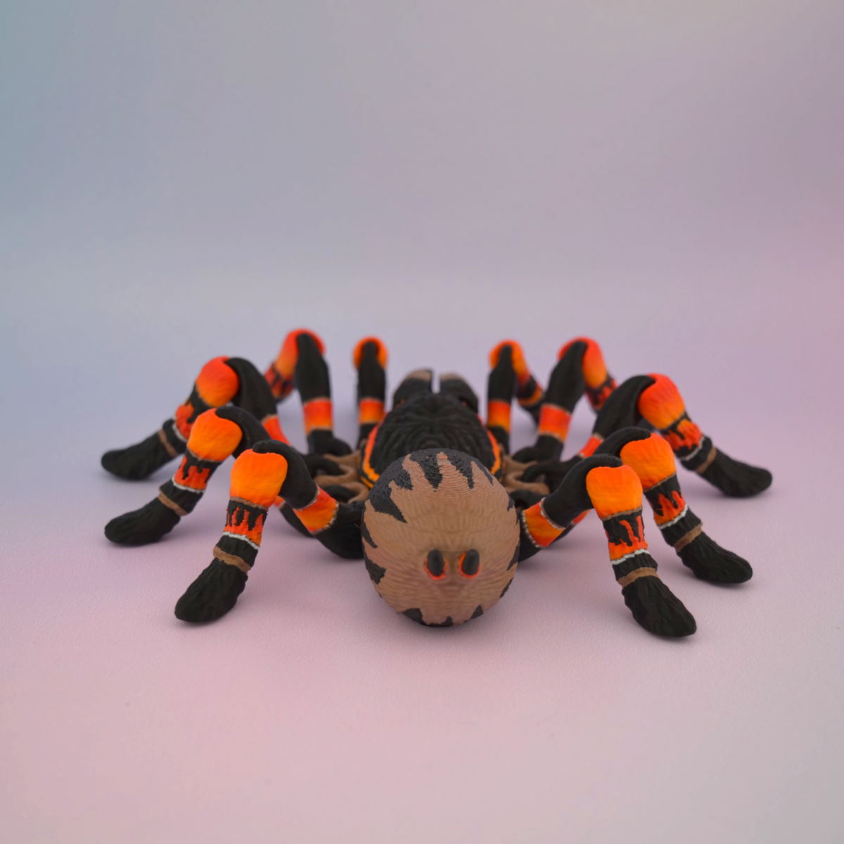 3D printed black tarantula with vibrant orange markings on its legs, displayed against a plain background.